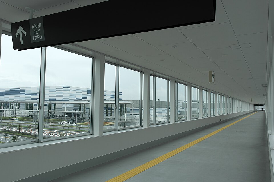 AICHI SKY EXPOへの矢印表示があるガラス張りの連絡通路と窓外の会場