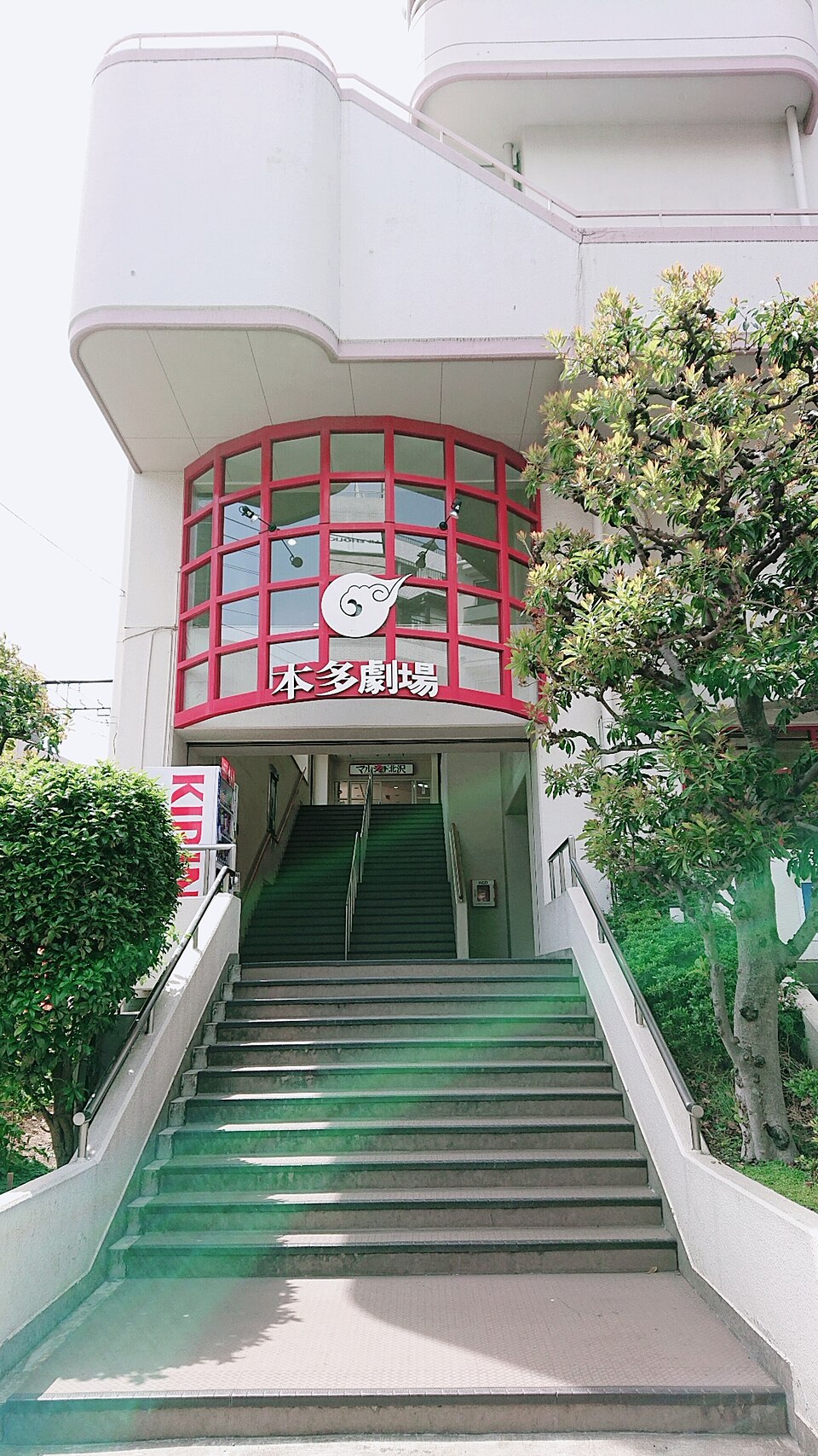 赤い本多劇場の看板の下から、入口へ向かって続く幅広い階段