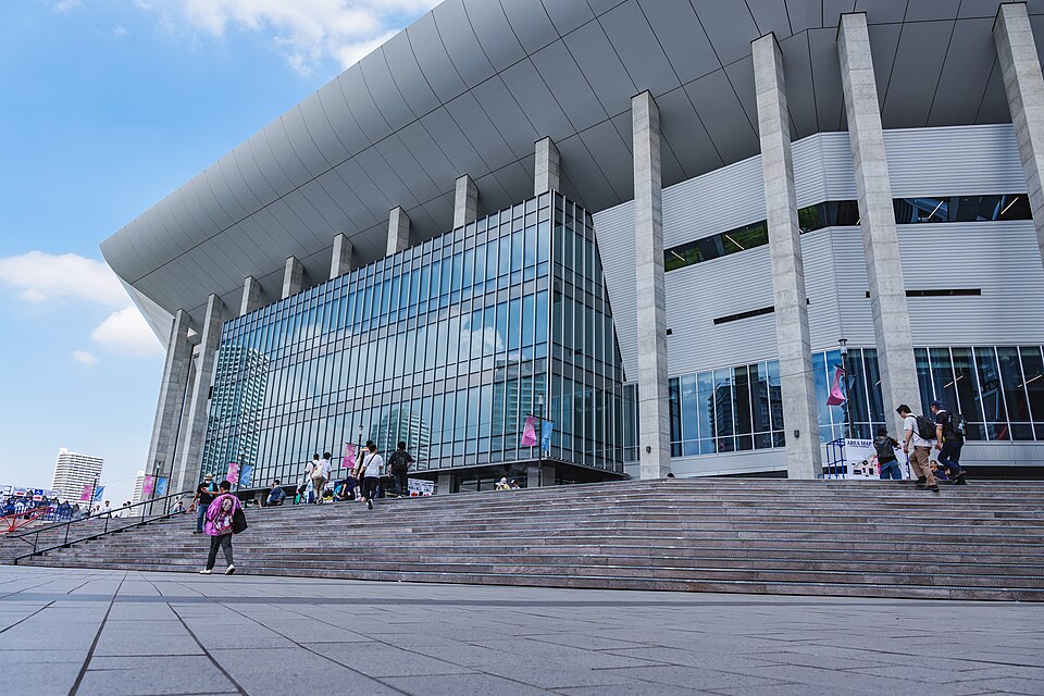 Kアリーナ横浜の大きなガラス面と入口前の階段、別公演の装飾や来場者が見える外観