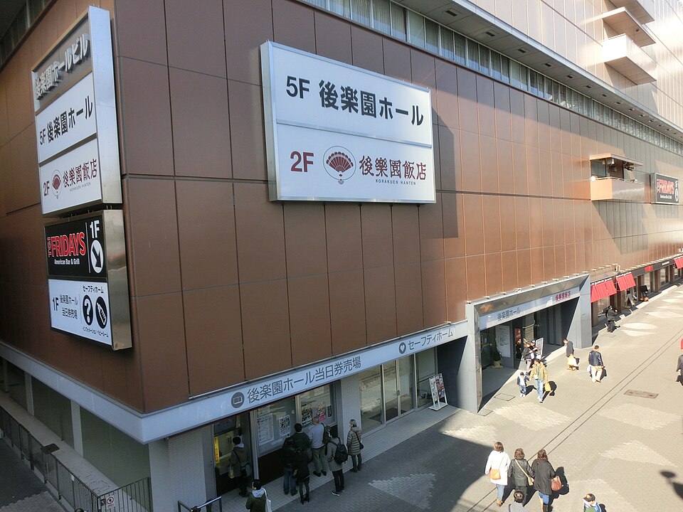 後楽園ホールビルの外壁に掲げられた5階ホールの案内と建物前の歩道