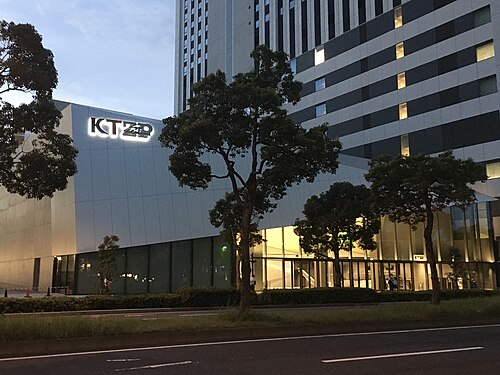 KT Zepp Yokohamaの明かりがついた看板とガラス張りの建物、夕方の歩道と道路