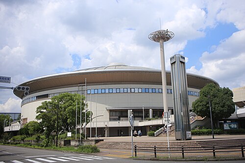 旧日本ガイシホールの入口側を道路越しに見た外観と階段、街路樹