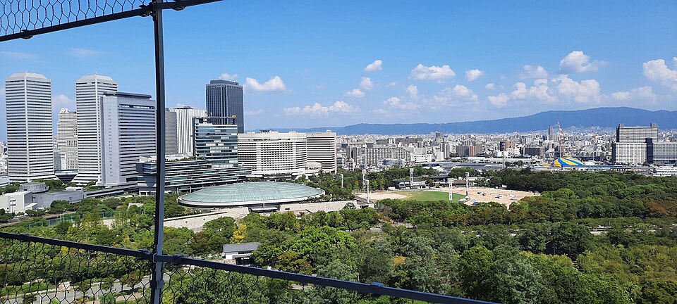 大阪城天守閣側から見た緑色の屋根の大阪城ホールと周辺の公園・ビル群