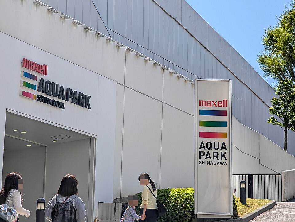 マクセルアクアパーク品川の白い外壁と大きな看板、その前を歩く人