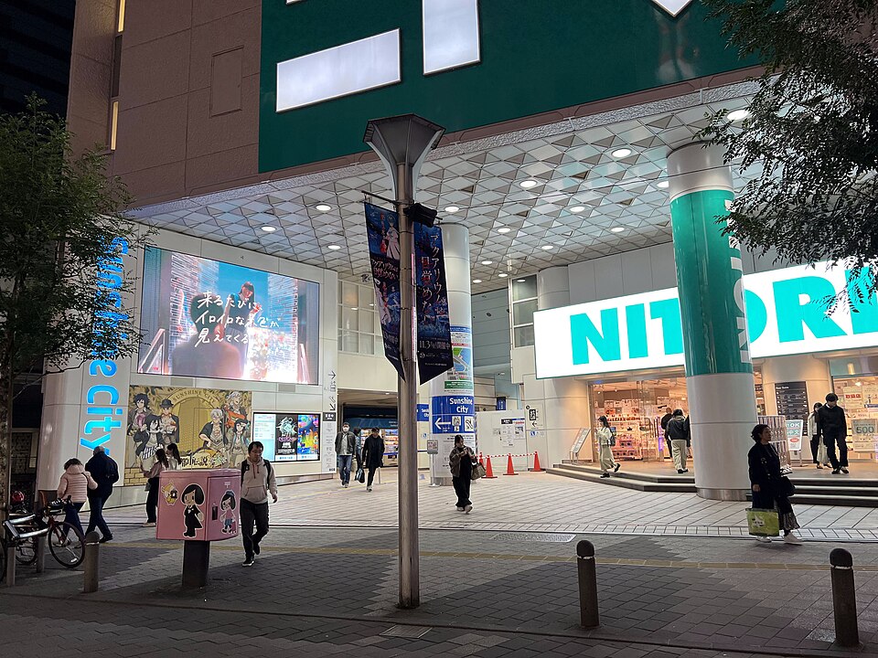 夜の通りから見たサンシャインシティの入口と大きな店舗看板