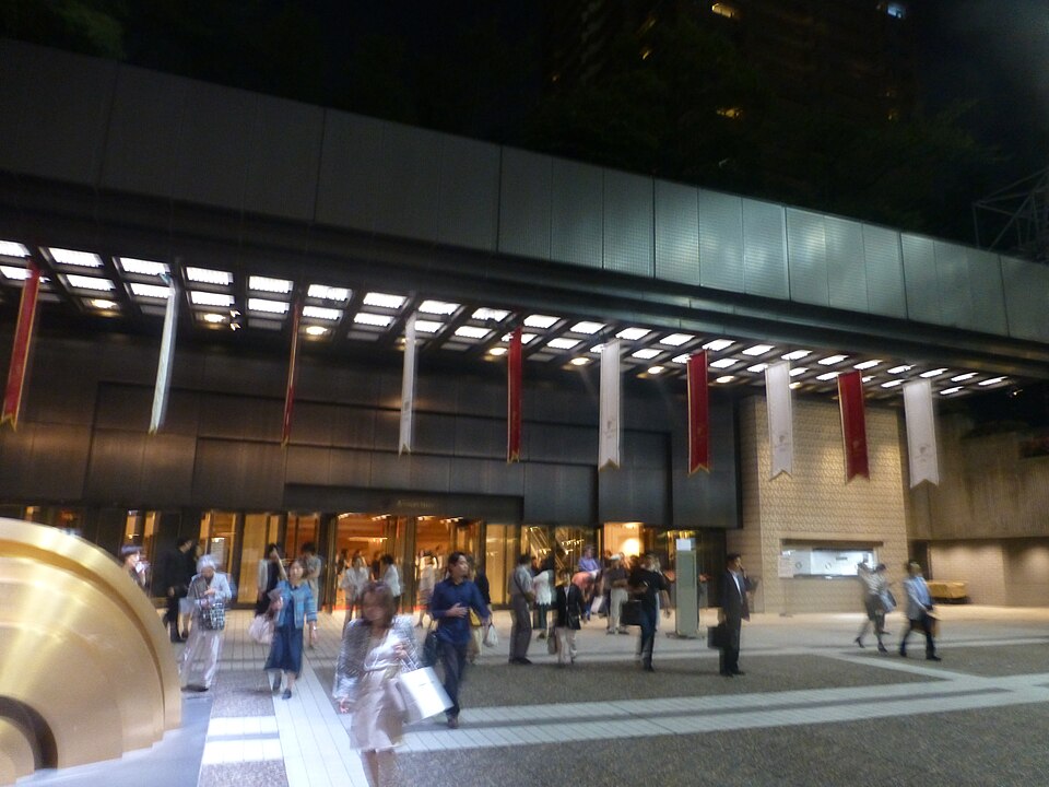 夜のサントリーホール入口、明るいひさしの下と広場を行き交う来場者