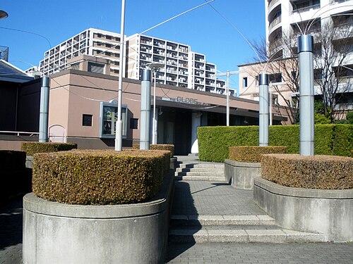 東京グローブ座の入口へ上がる階段、銀色の柱と植栽、背後の集合住宅