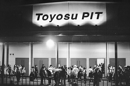 Toyosu PITの看板がある夜の入口前と来場者を写した白黒写真