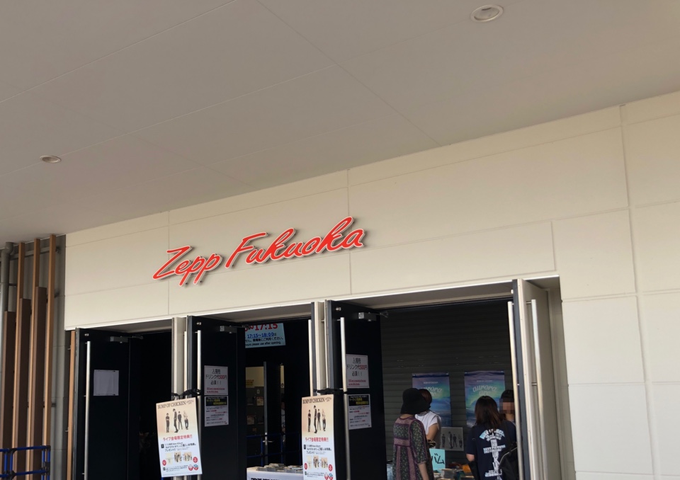 白い壁に赤いZepp Fukuokaの看板があり、扉と公演時の案内が並ぶ入口まわり