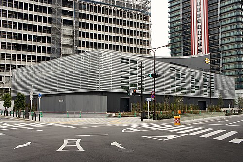 横格子で囲まれたZepp Nambaの建物と歩道、背景で建設中の高層建物