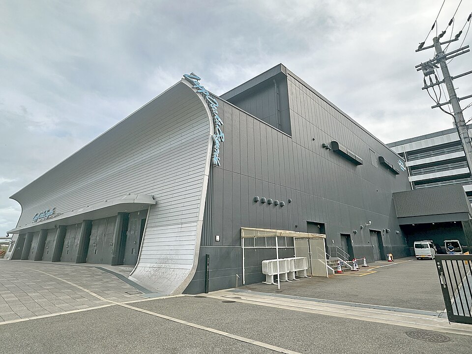 銀色の曲がった屋根とZepp Osaka Baysideの看板、建物前の舗装と側面が見える外観